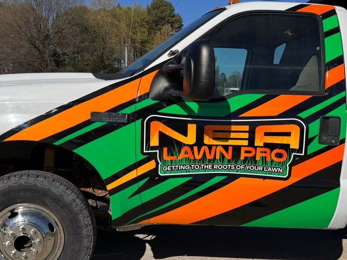 NEA Lawn Pro dump truck with a green, orange, and black partial wrap